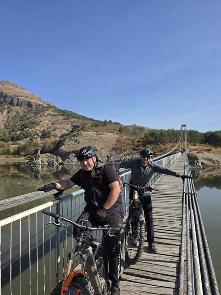 Two riders with their bikes on the suspension bridge