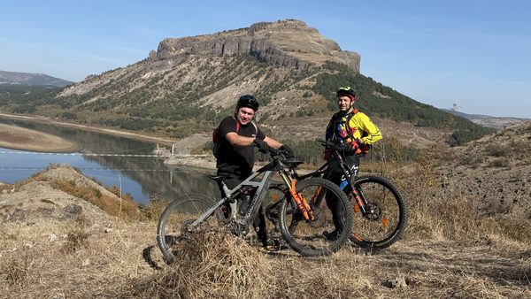 Two riders below the flat-topped hill